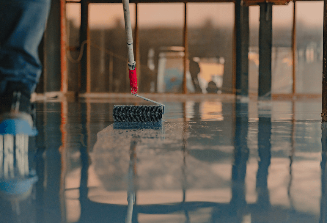 A worker applying resin flooring to a food and beverage warehouse floor.